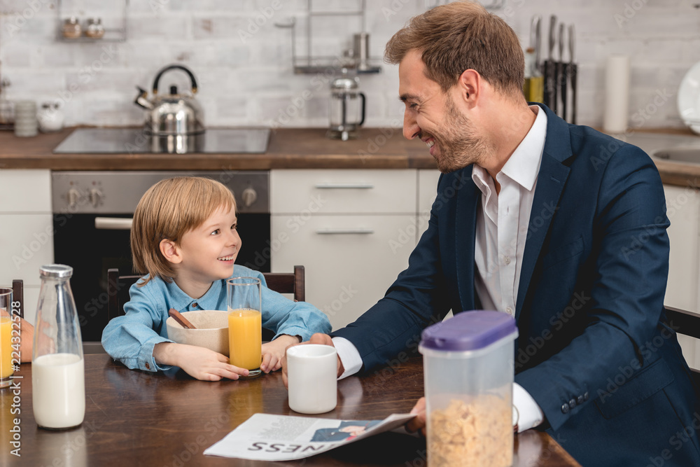 father and son laughing together at kitchen during breakfast father and son laughing together at kitchen during breakfast