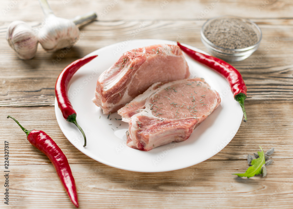 Raw pork ribs with red pepper, garlic and seasonings on a wooden background. Raw pork ribs with red pepper, garlic and seasonings on a wooden background.
