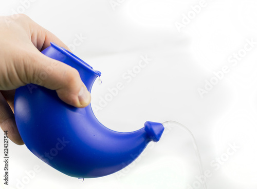 Use of a device for washing the nose. The hand holds the device with a pouring solution for rinsing on a white background. photo