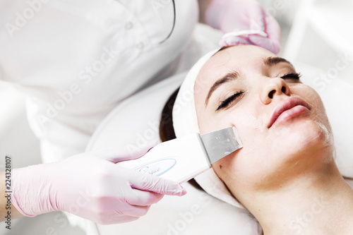 The cosmetologist in pink gloves makes the procedure Microdermabrasion of the facial skin of a beautiful, young woman in a beauty salon.Cosmetology and professional skin care. Skin Care.