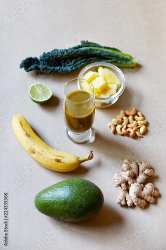 Above view of avocado banana binger pineapple and kale ingredients over a textured brown flat lay background in studio photo