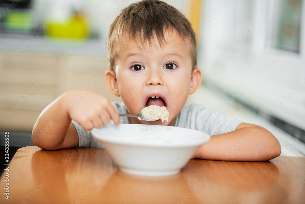 charming child in the kitchen eating oatmeal charming child in the kitchen eating oatmeal