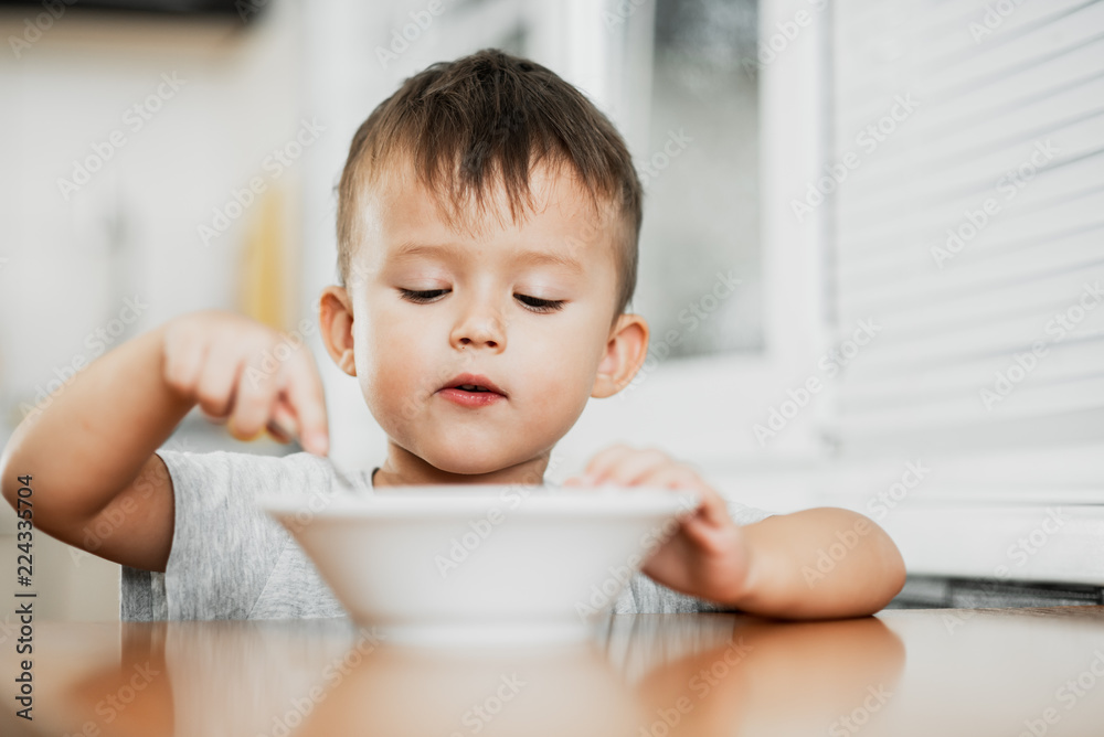 charming child in the kitchen eating oatmeal charming child in the kitchen eating oatmeal
