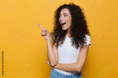 Young cute woman posing isolated over yellow background pointing.