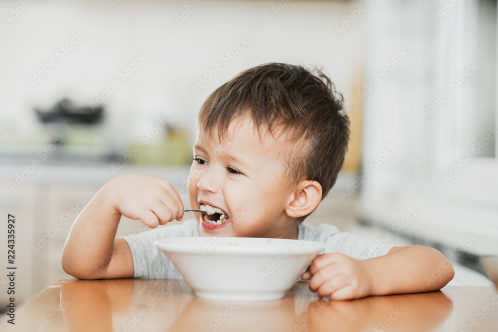 charming child in the kitchen eating oatmeal charming child in the kitchen eating oatmeal
