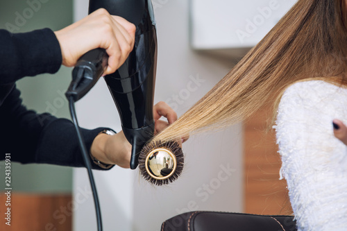 Young beautiful woman client doing styling at a professional hairdresser in a beauty salon close-up