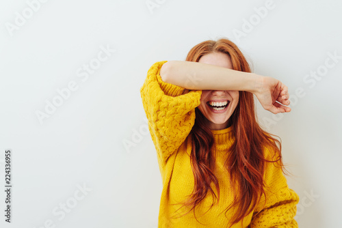 laughing woman covering her eyes with her arm