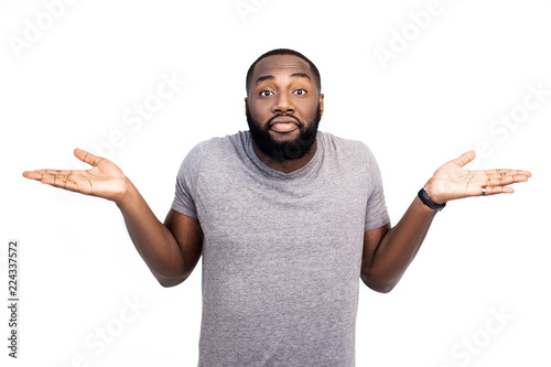 Uncertain hesitant black man shrug shoulders in bewilderment, can`t understand question, has serious confused expression, poses against pink studio background. Body language and people concept photo