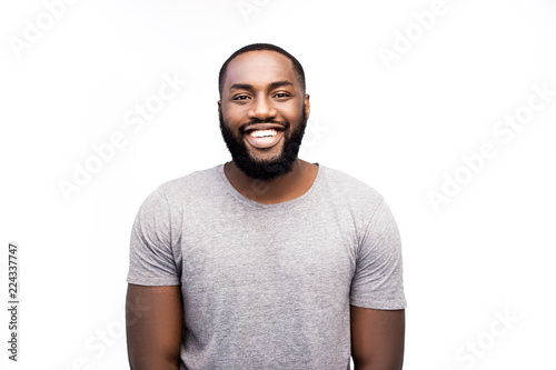 Handsome unshaven young dark-skinned male laughing out loud at funny meme he found on internet, smiling broadly, showing his white straight teeth. Positive human facial expressions, emotions, friendly