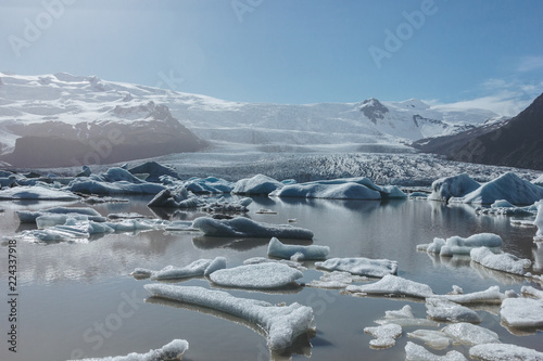 melting glacier ice floating in lake in Fjallsarlon, Iceland under blue sky photo