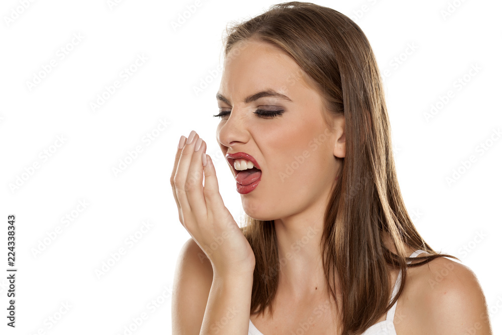 Beautiful girl checking her breath on white background