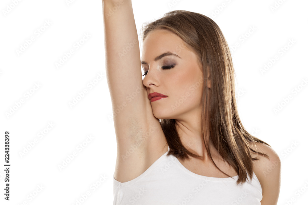 Beautiful girl smelling her armpit on white background Beautiful girl smelling her armpit on white background