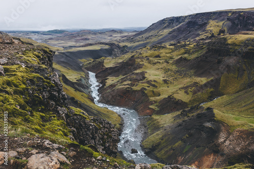 aerial view of curvy river streaming in green hills in Iceland on cloudy day