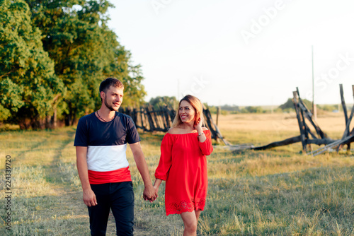 Young beautiful enamored couple walking outdoors in summer at sunset