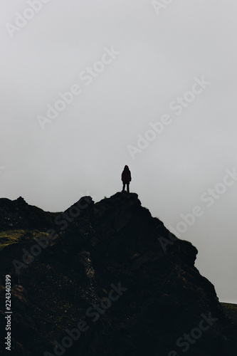 Silhouette of woman standing on mountain in front of cloudy sky