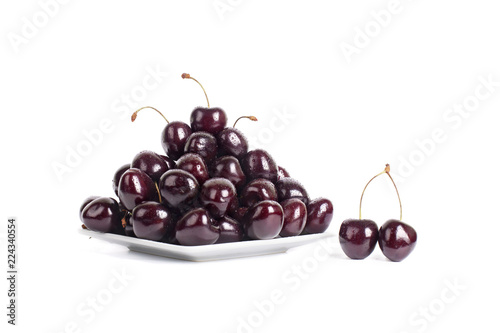A lot of cherries in drops of water on a white plate isolated closeup macro