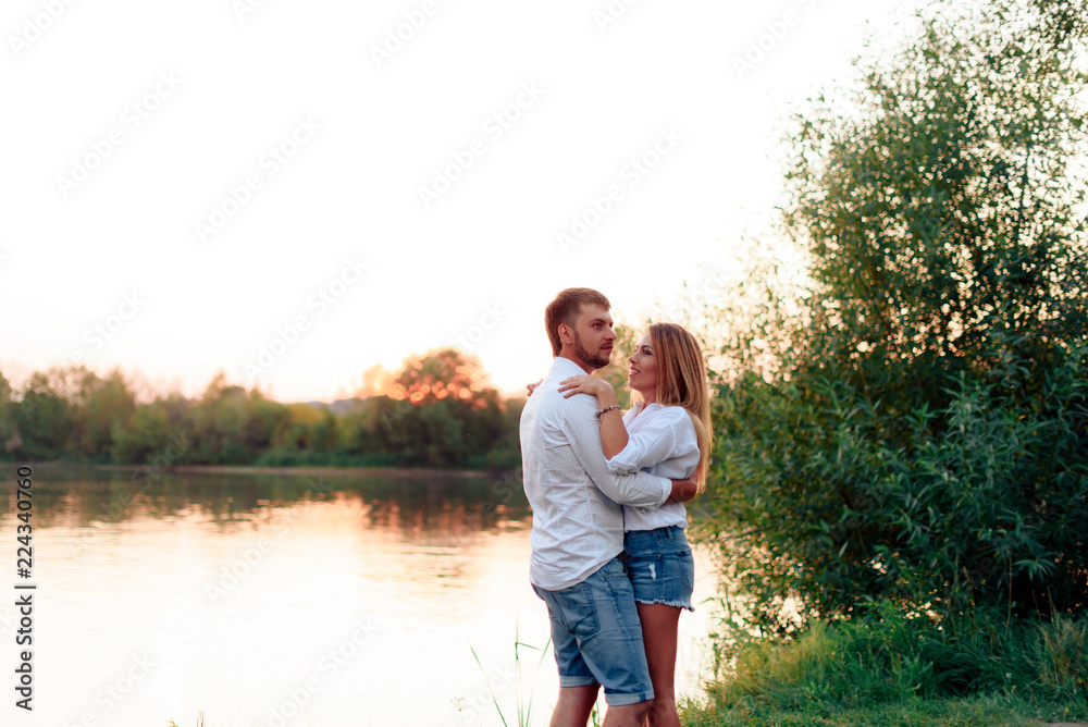Young beautiful enamored couple walking outdoors in summer at sunset Young beautiful enamored couple walking outdoors in summer at sunset