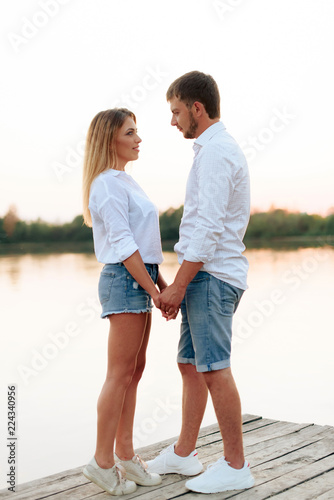 Young beautiful enamored couple walking outdoors in summer at sunset