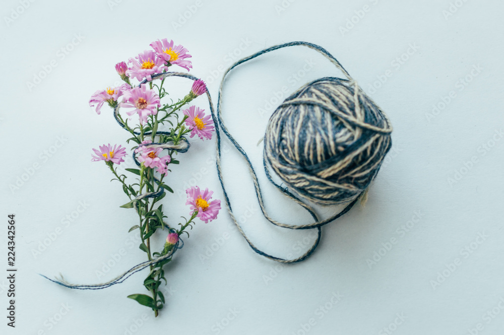 Yarn on a blue background and pink flowers. Concept yarn for knitting Yarn on a blue background and pink flowers. Concept yarn for knitting