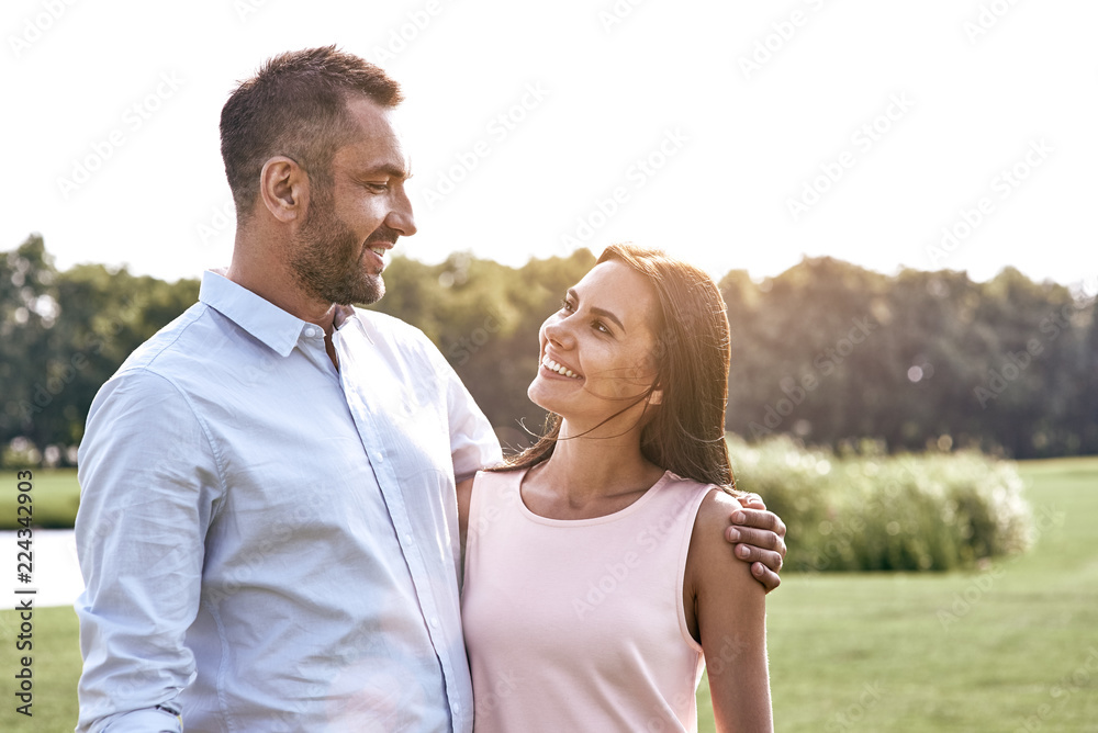 Fototapeta premium Romantic time. Young couple standing in the park hugging looking