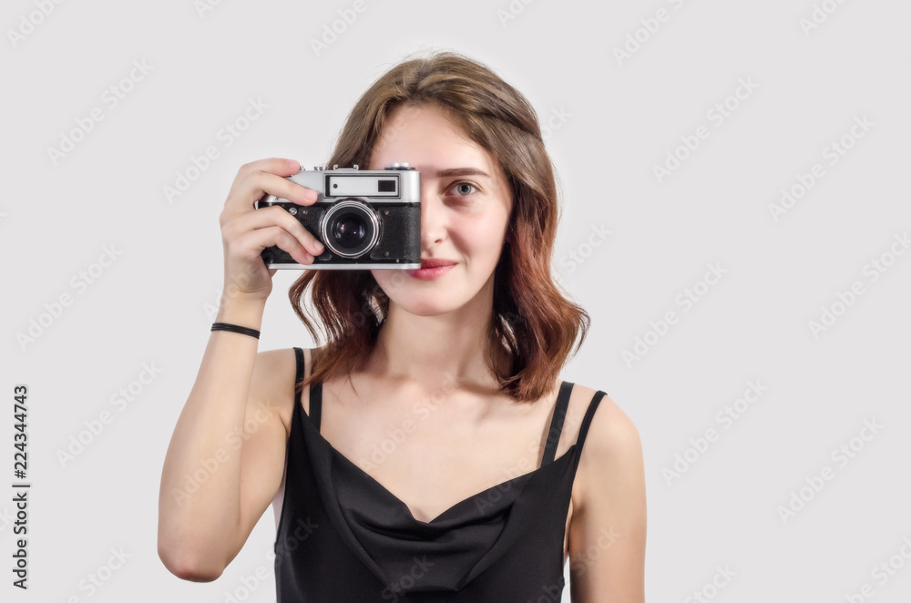 beautiful young girl in a short black dress takes pictures with an old vintage camera, a smile, a beautiful face, a brunette. beautiful young girl in a short black dress takes pictures with an old vintage camera, a smile, a beautiful face, a brunette.