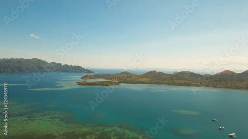 Aerial view: beach, tropical island, sea bay and lagoon, mountains with rainforest, Palawan. Lagoon with blue, azure water in the middle of small islands and rocks. Busuanga. Seascape, tropical