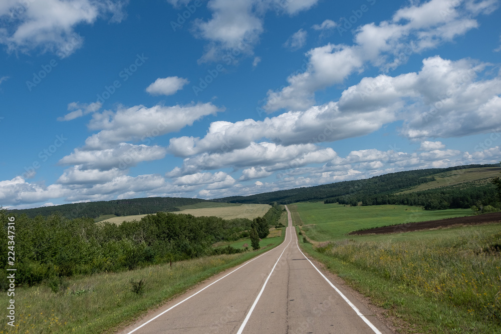 An asphalt road with white markings stretching into the distance. An asphalt road with white markings stretching into the distance.