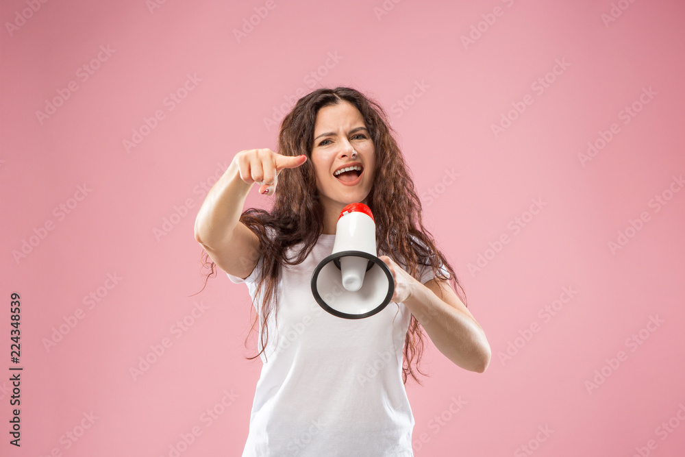 Obraz premium Woman making announcement with megaphone at pink studio. Human facial emotions concept. Trendy colors