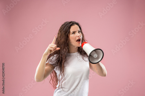 Woman making announcement with megaphone at pink studio. Human facial emotions concept. Trendy colors