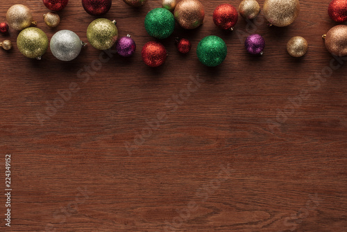 top view of beautiful shiny colorful baubles on wooden surface, christmas background