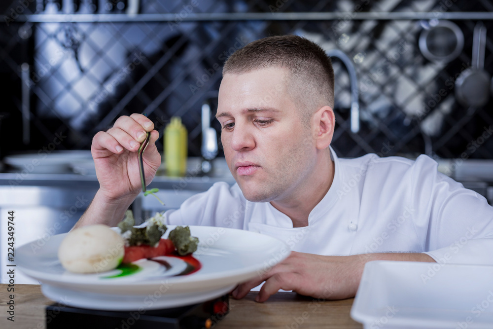 Even more delicious. Attentive nice cook being concentrated while adding new ingredients to a dish