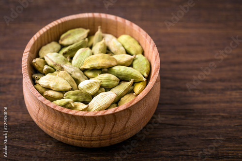 Cardamom, pods in a cup on a wooden background, Indian spice