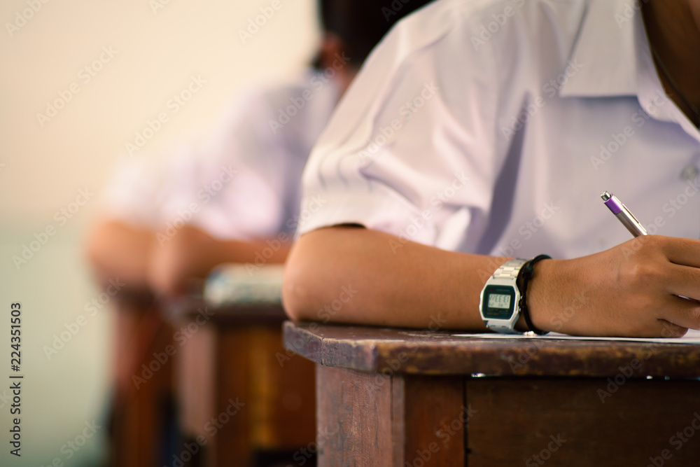 Fototapeta premium School students taking exam writing answer in classroom with stress