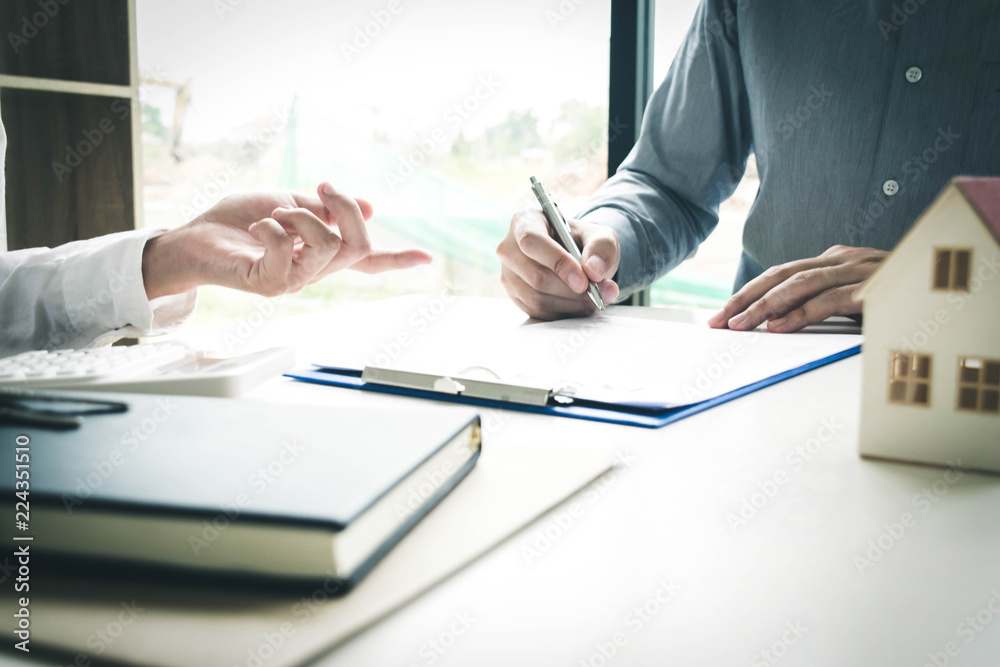 The young man is signing a lease agreement with the capitalist and checking the securities to ensure that the young man can rent the house completely. The young man is signing a lease agreement with the capitalist and checking the securities to ensure that the young man can rent the house completely.