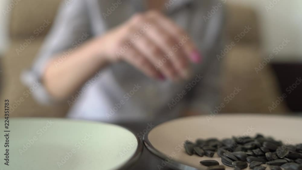female hands close up take sunflower seeds from dishes on the table female hands close up take sunflower seeds from dishes on the table