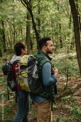 side view of man and woman with backpacks hiking in woods together