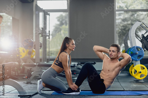 Woman holding man feet down as he doing sit up exercises.