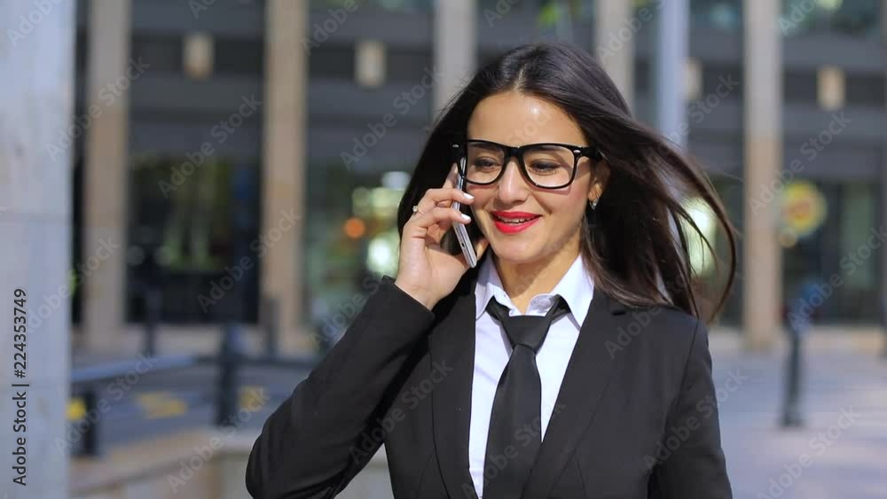 Cute businesswoman walking talking on mobile phone. Steadicam shot, slow motion Cute businesswoman walking talking on mobile phone. Steadicam shot, slow motion