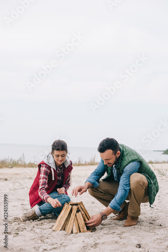 couple making campfire on sandy beach