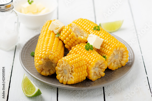 Homemade golden sweet corn cob with butter and salt on white table. top view.