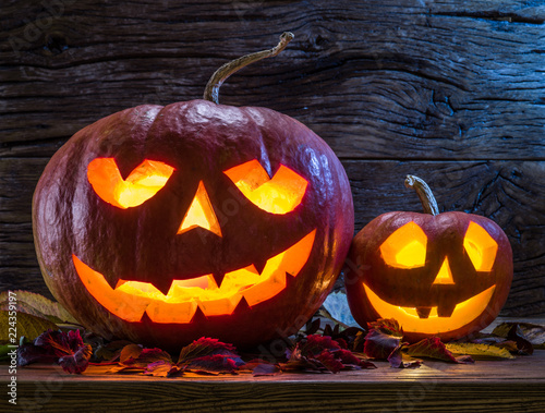 Grinning pumpkin lantern or jack-o'-lantern is one of the symbols of Halloween. Halloween attribute. Wooden background.