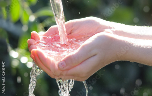bambina che raccoglie acqua purissima con le mani