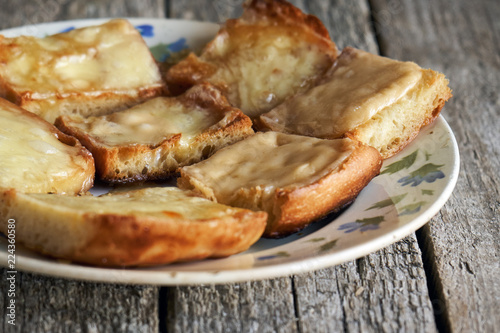 Toasts with melted cheese in an old plate on wooden boards