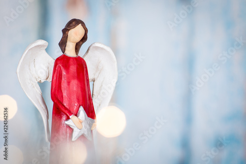 Christmas background with red angel holding a star on blue background with lights