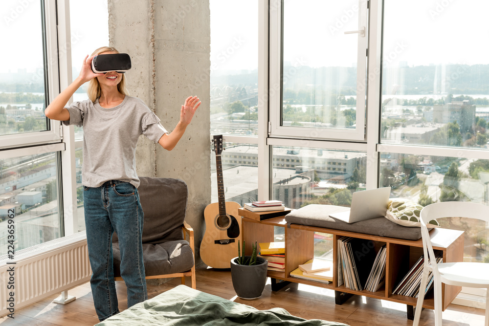 young cheerful woman in vr headset gesturing at home young cheerful woman in vr headset gesturing at home