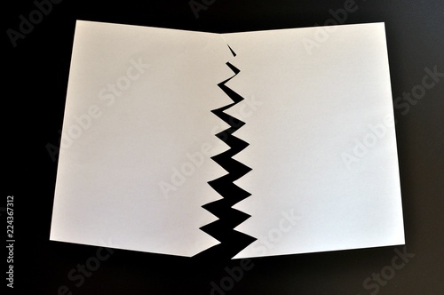 Concept of divided or separated torn paper in two sheets. White paper ripped in half isolated on black background. Top view