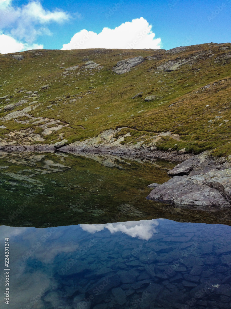 panoramic view of an alpine lake, where the Swiss mountains are mirrored at the Simplon pass.