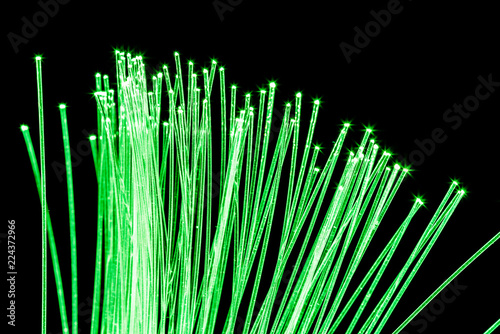 Bundle of optical fibers with green light. Black background.