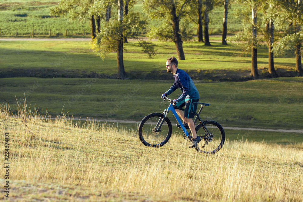 A cyclist rides the hills, Beautiful portrait of a guy on a blue bicycle	