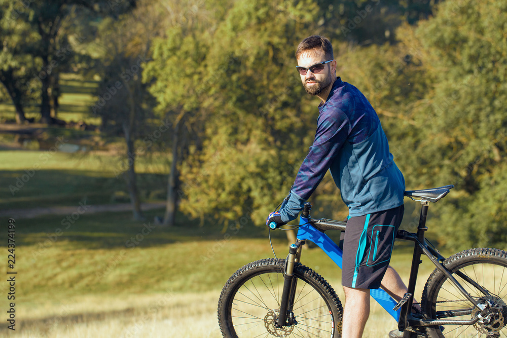 A cyclist rides the hills, Beautiful portrait of a guy on a blue bicycle A cyclist rides the hills, Beautiful portrait of a guy on a blue bicycle